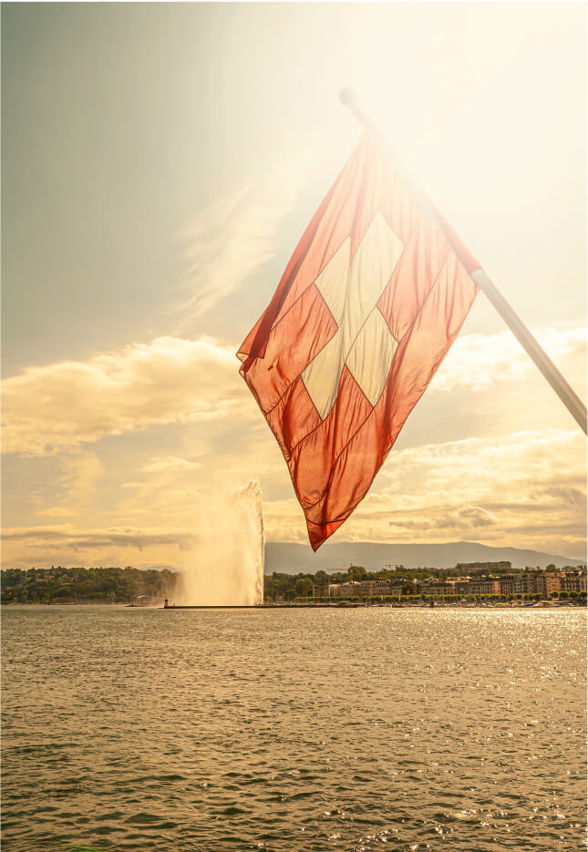 Swiss flag near Geneva fountain at sunset