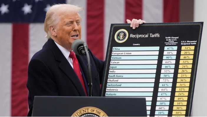 Person presenting tariffs chart at podium outdoors.
