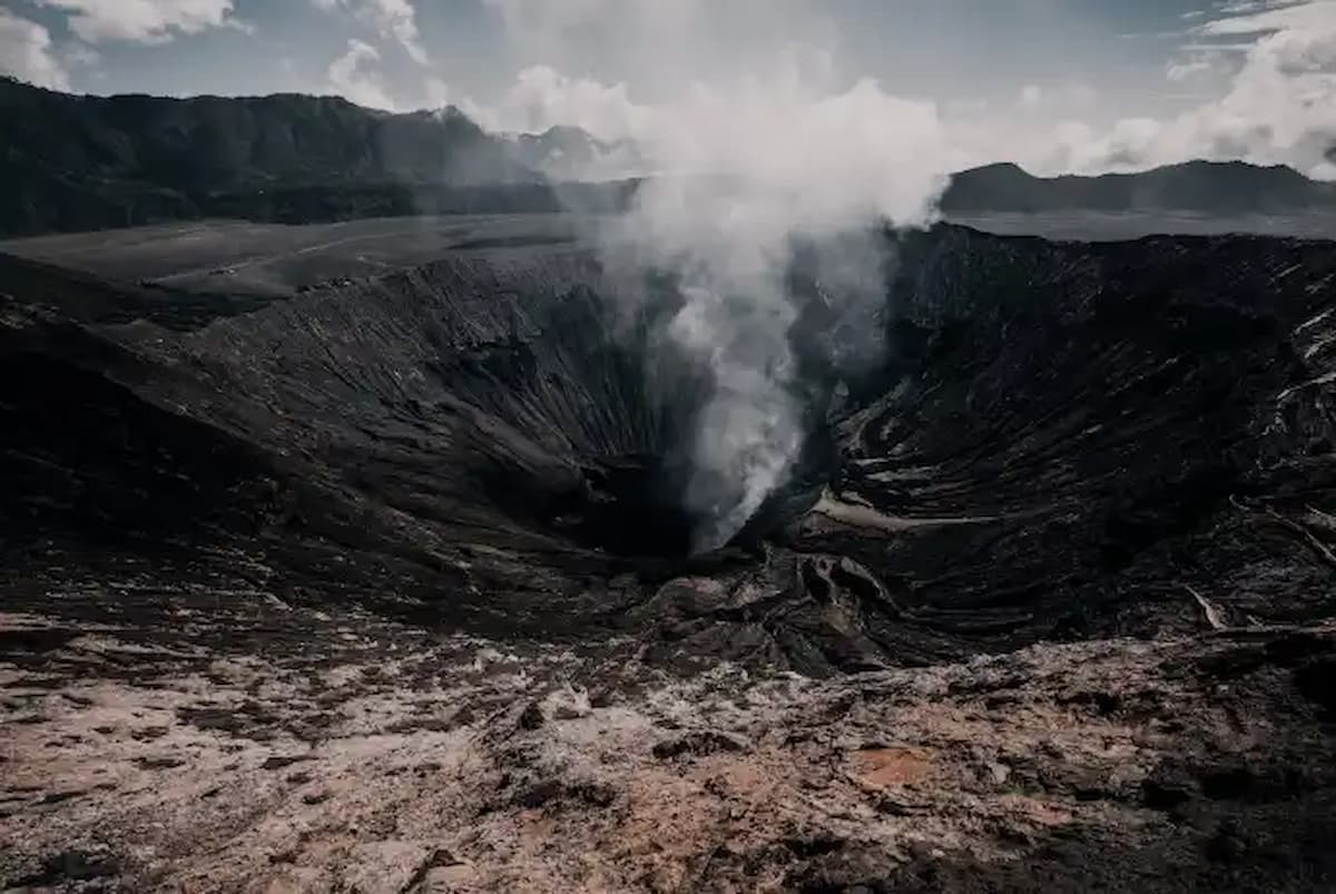 Smoking volcanic crater under cloudy sky
