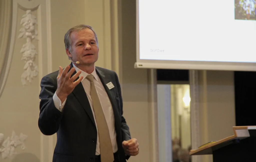 Man speaking at conference with microphone.