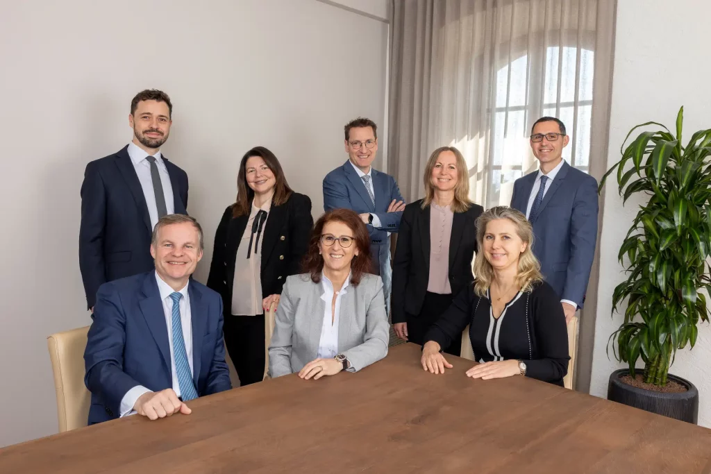 Team of professionals posing around a table.