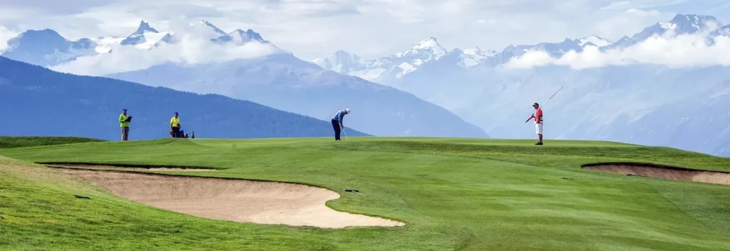 Golfers on course with mountain views.