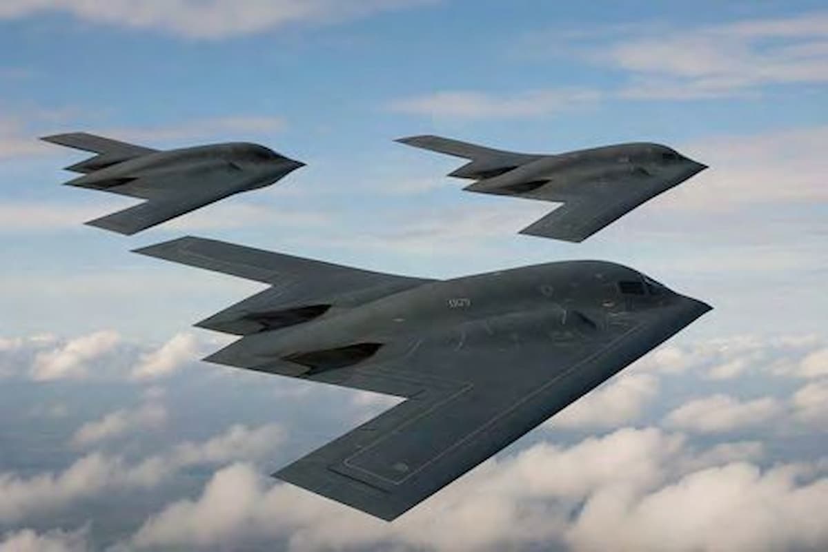 Three stealth bombers flying above clouds.