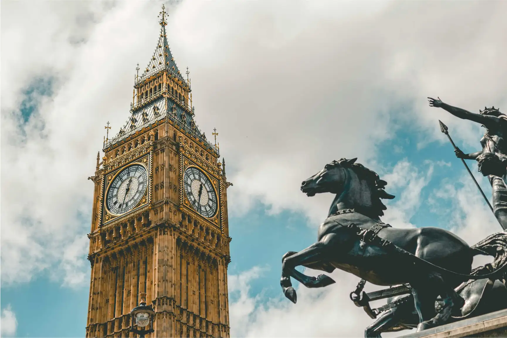 Big Ben and Boudica statue against cloudy sky