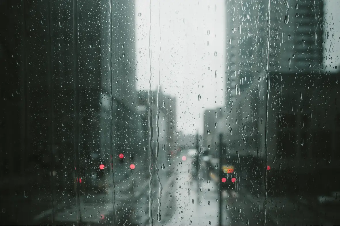 Rainy cityscape viewed through window with raindrops.