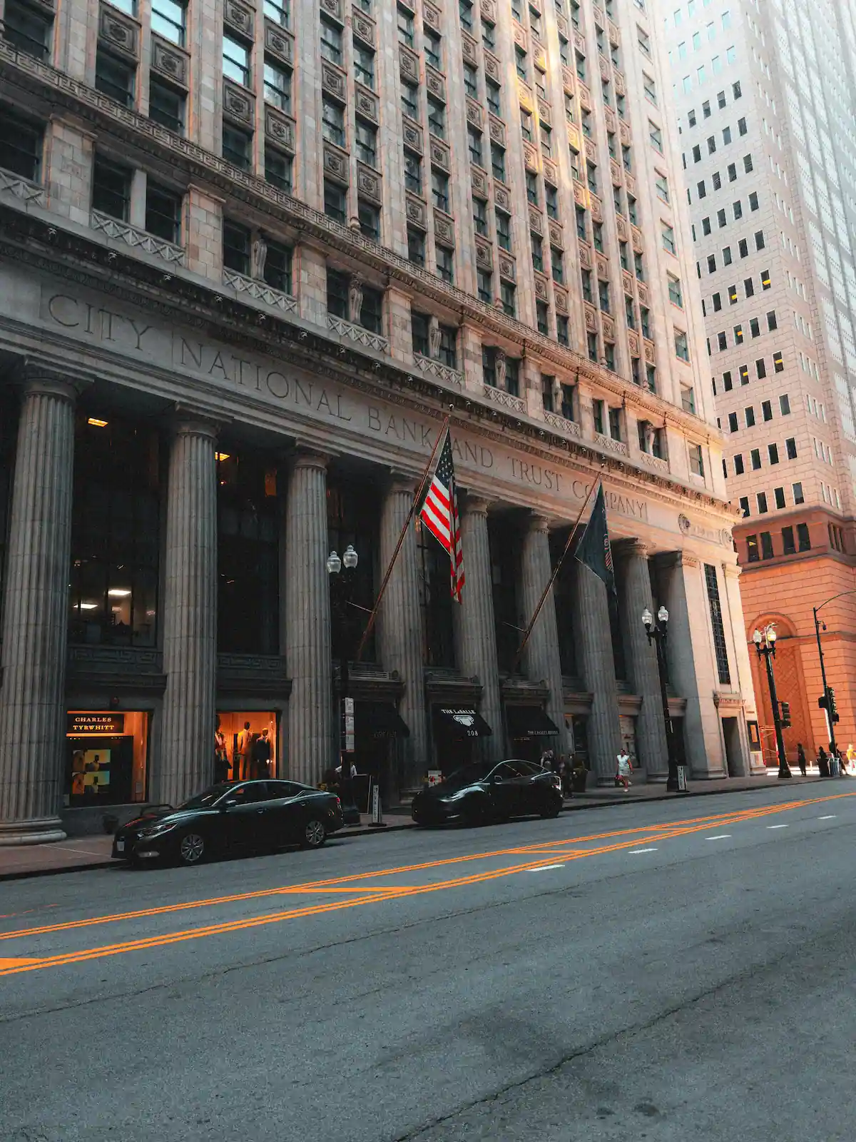 Historic city bank building with American flags outside.