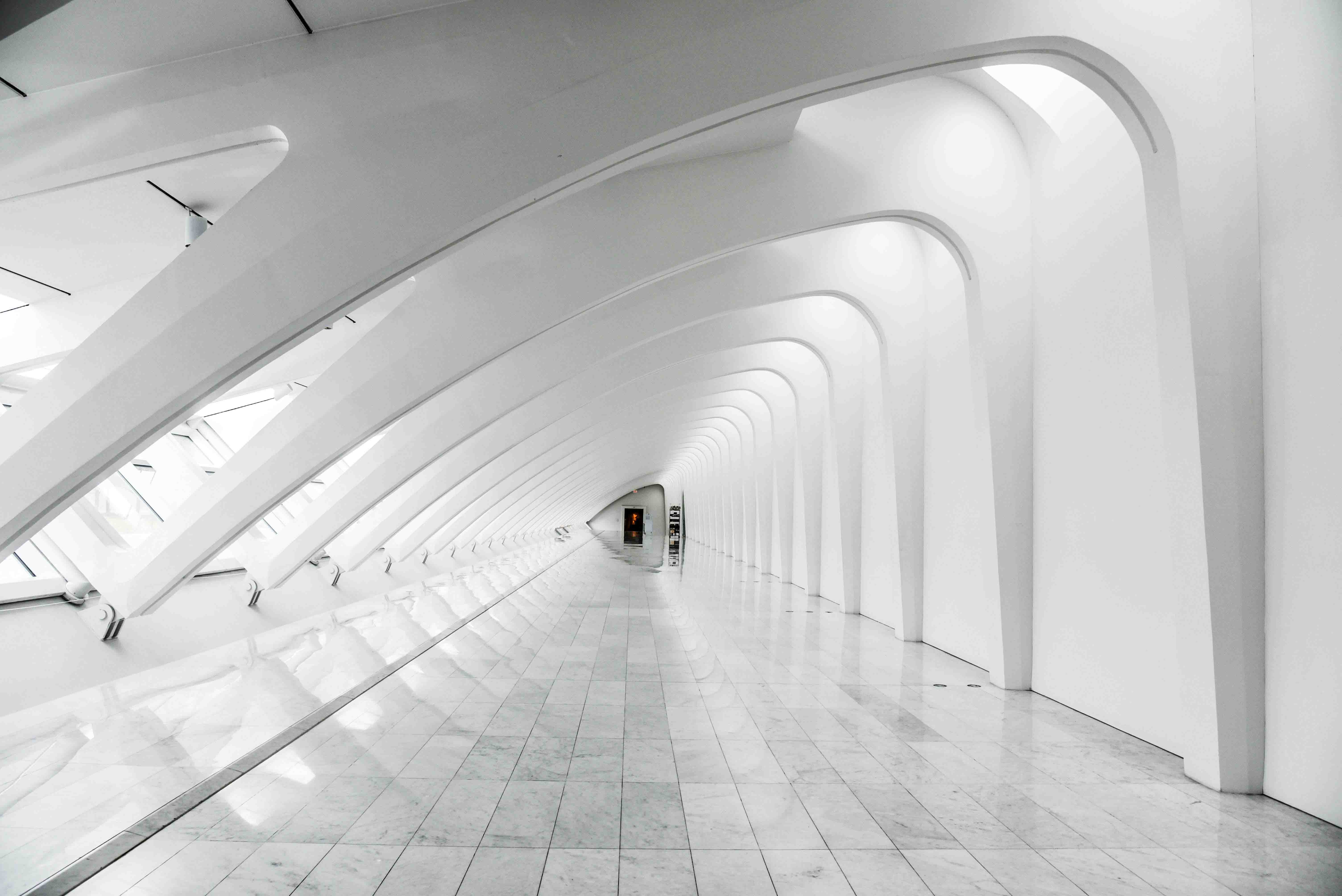 Couloir futuriste avec arches blanches et plafond lumineux.