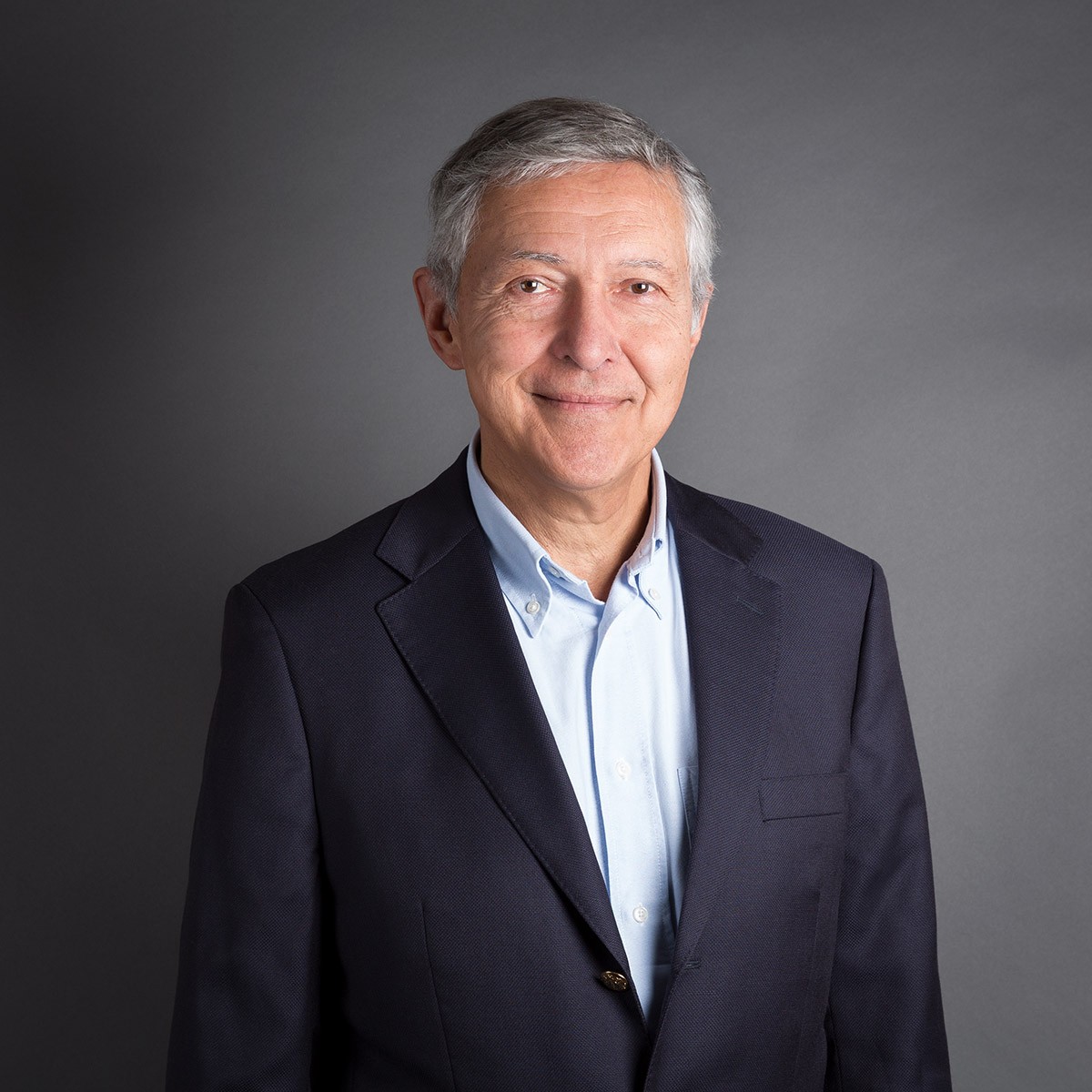 Smiling man in suit with gray background.